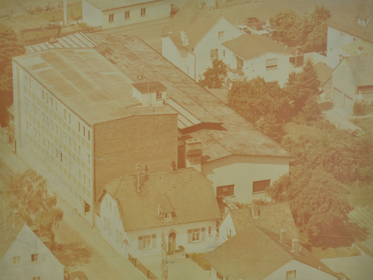 Das Luftbild zeigt ein großes Gebäude in Strullendorf und weitere Häuser um die Fertigungshalle. Das Luftbild stammt aus dem Jahr 1960. KACHELMANN GETRIEBE GmbH