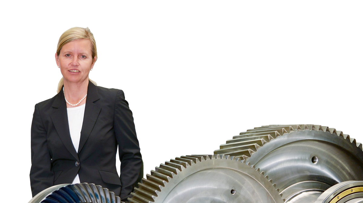 Die Geschäftsführerin Andrea von Wartenberg der Firma KACHELMANN GETRIEBE GmbH lehnt auf der linken Seite an einem Getriebe, während sie in die Kamera lächelt. KACHELMANN GETRIEBE GmbH