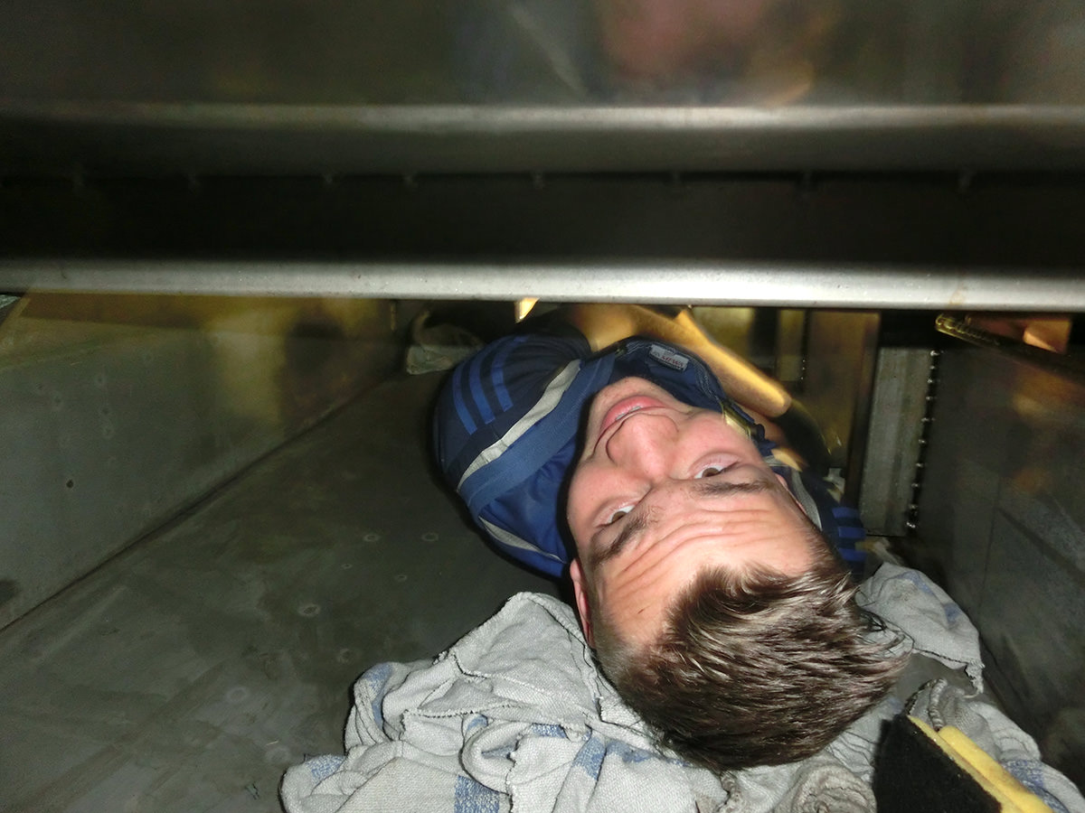Der Azubi der Firma KACHELMANN GETRIEBE GmbH steht in einem Schacht und schaut nach oben in die Kamera. Dabei lacht er. Hinter ihm liegt ein Handtuch. KACHELMANN GETRIEBE GmbH