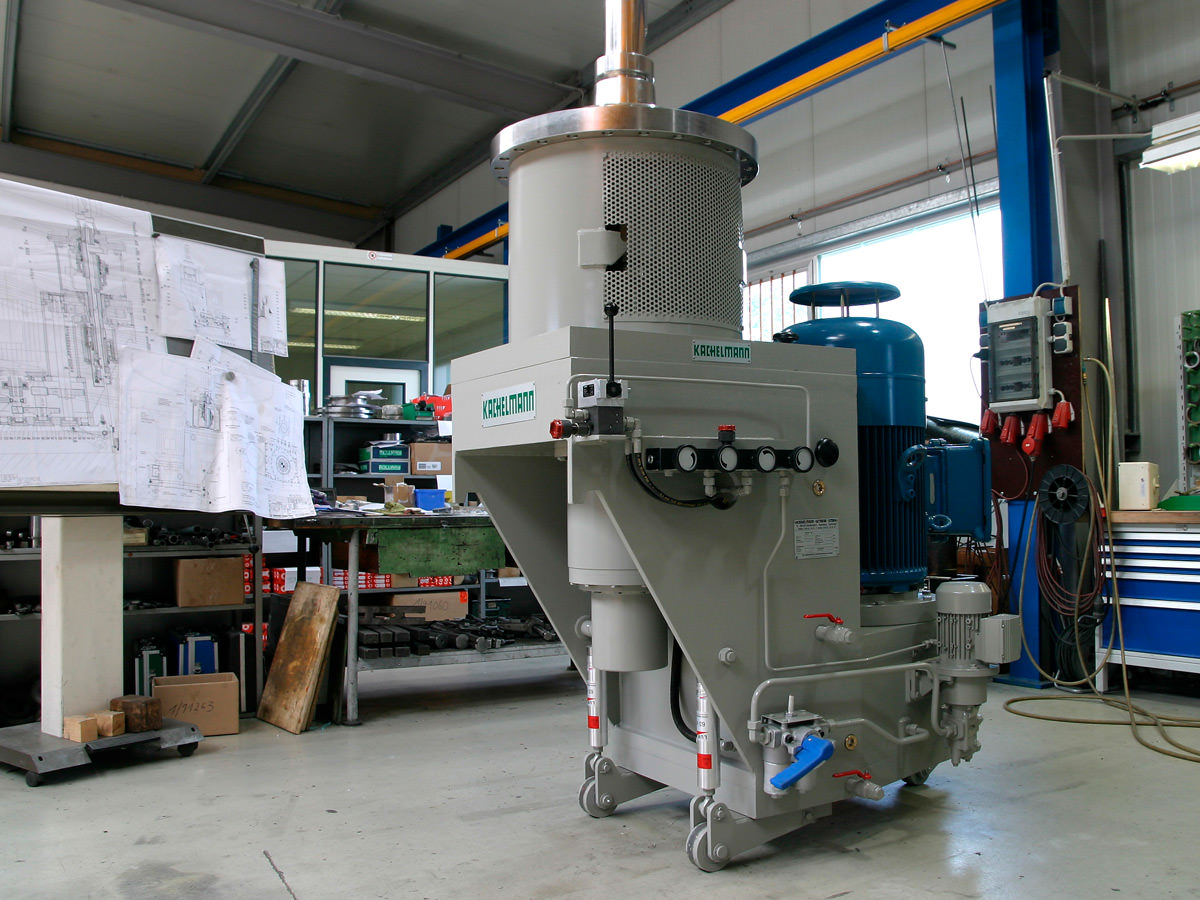 In der Fertigungshalle der Firma KACHELMANN GETRIEBE GmbH wird das Rührwerksgetriebes mit Schnellwechseleinrichtung gefertigt. Im Hintergrund sind technische Zeichnungen und Werkzeuge zu erkennen. KACHELMANN GETRIEBE GmbH